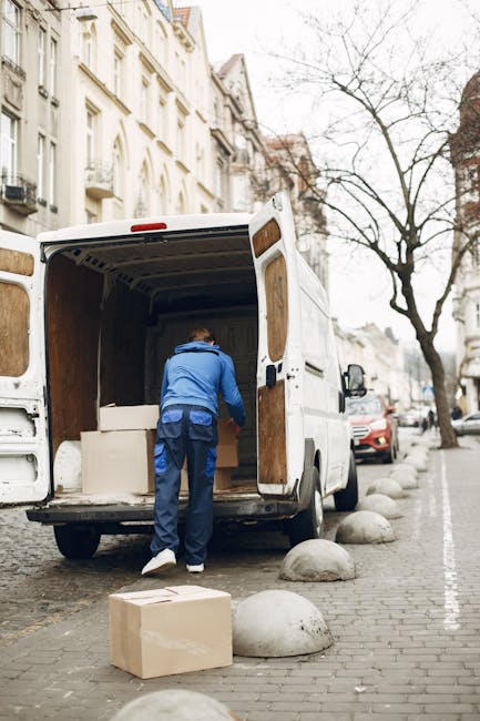 A professional moving company in the process of a home relocation, with numerous cardboard boxes, some sealed with packing tape and others open revealing packing materials like bubble wrap and tissue