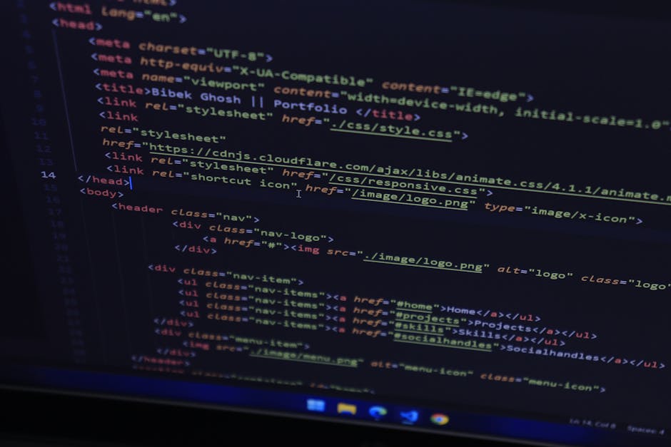 A silver MacBook laptop opened on a white desk, displaying a dark-themed code editor with lines of colourful programming code. Next to the laptop, an iPhone is placed face-up, and to the left, there i